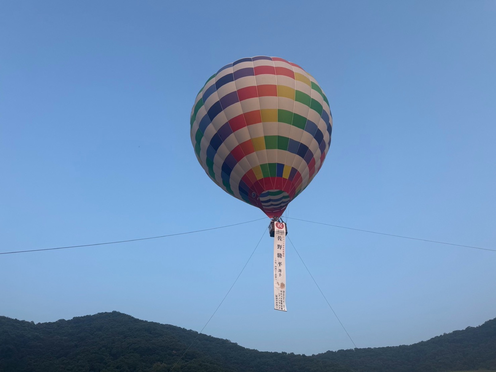 祝福の垂れ幕を掲げて上がった気球